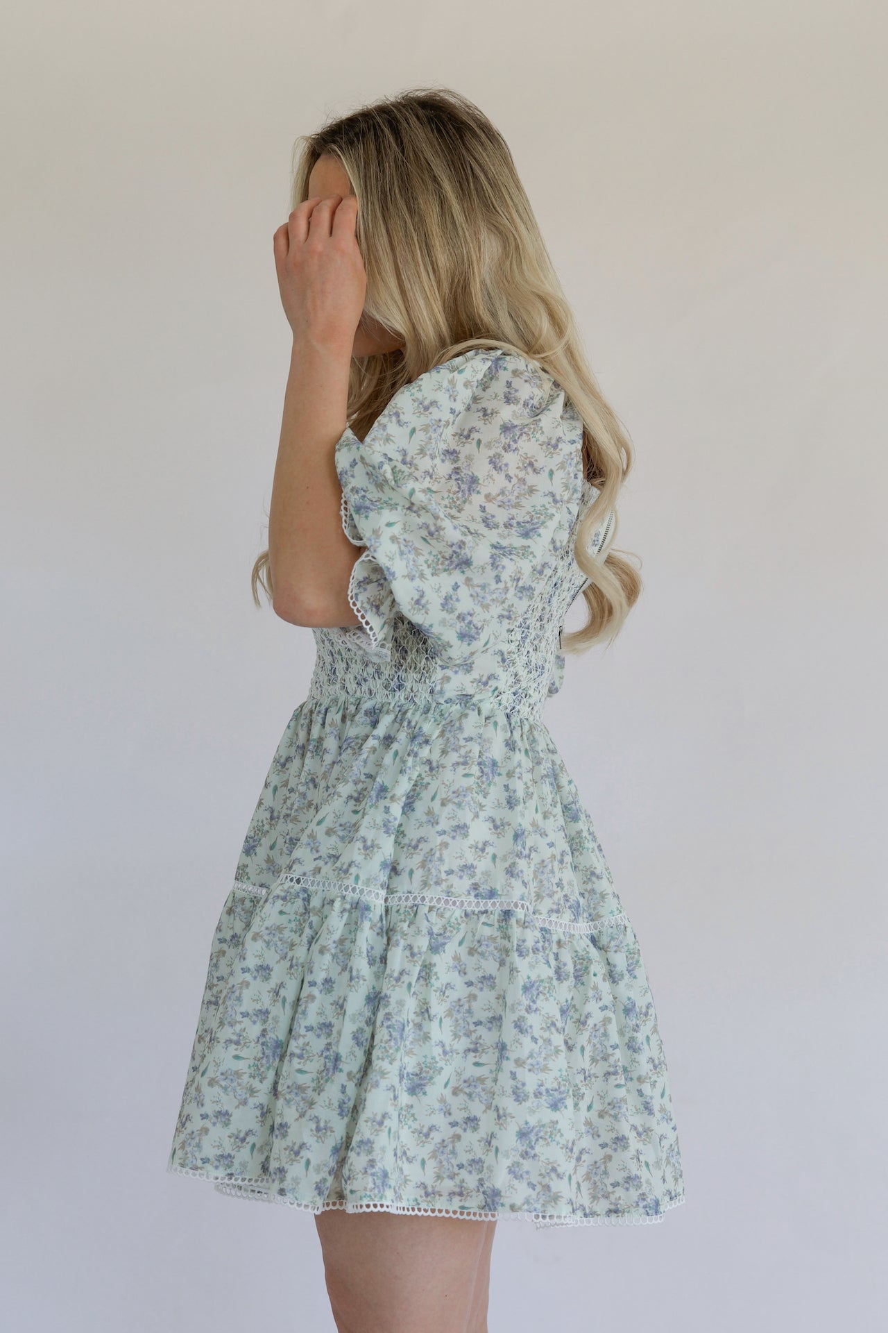 blue floral mini dress with puff sleeves, smocked bodice, tiered, and crochet lace trim