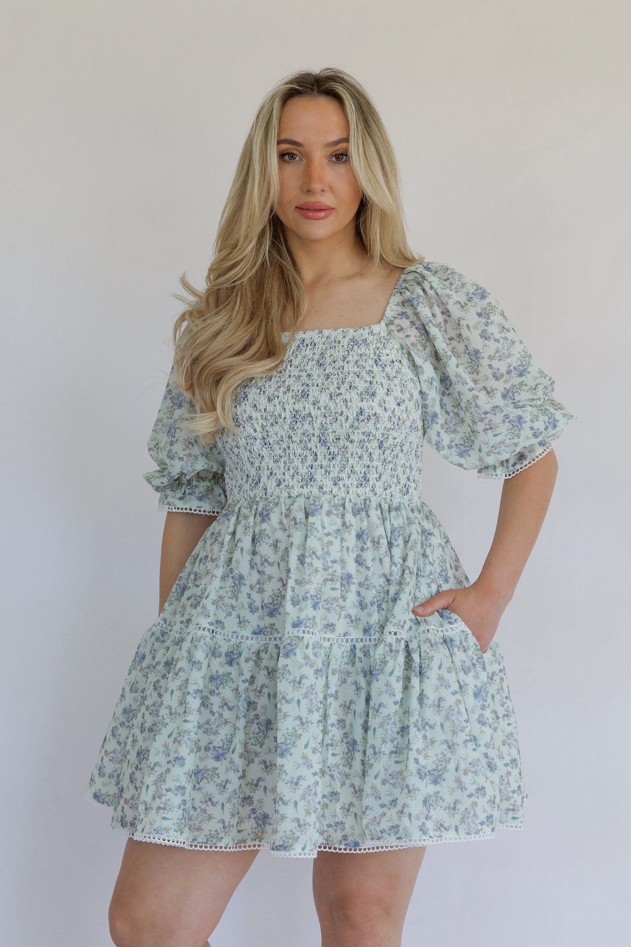 blue floral mini dress with puff sleeves, smocked bodice, tiered, and crochet lace trim