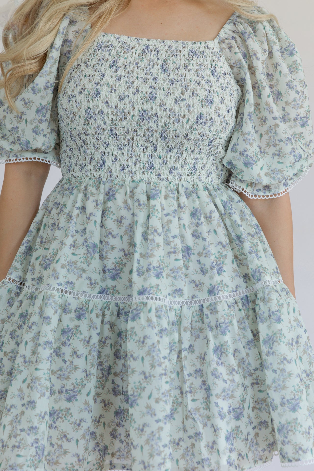 blue floral mini dress with puff sleeves, smocked bodice, tiered, and crochet lace trim