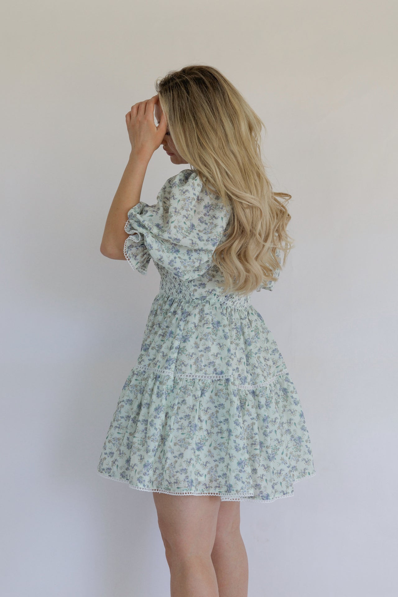 blue floral mini dress with puff sleeves, smocked bodice, tiered, and crochet lace trim
