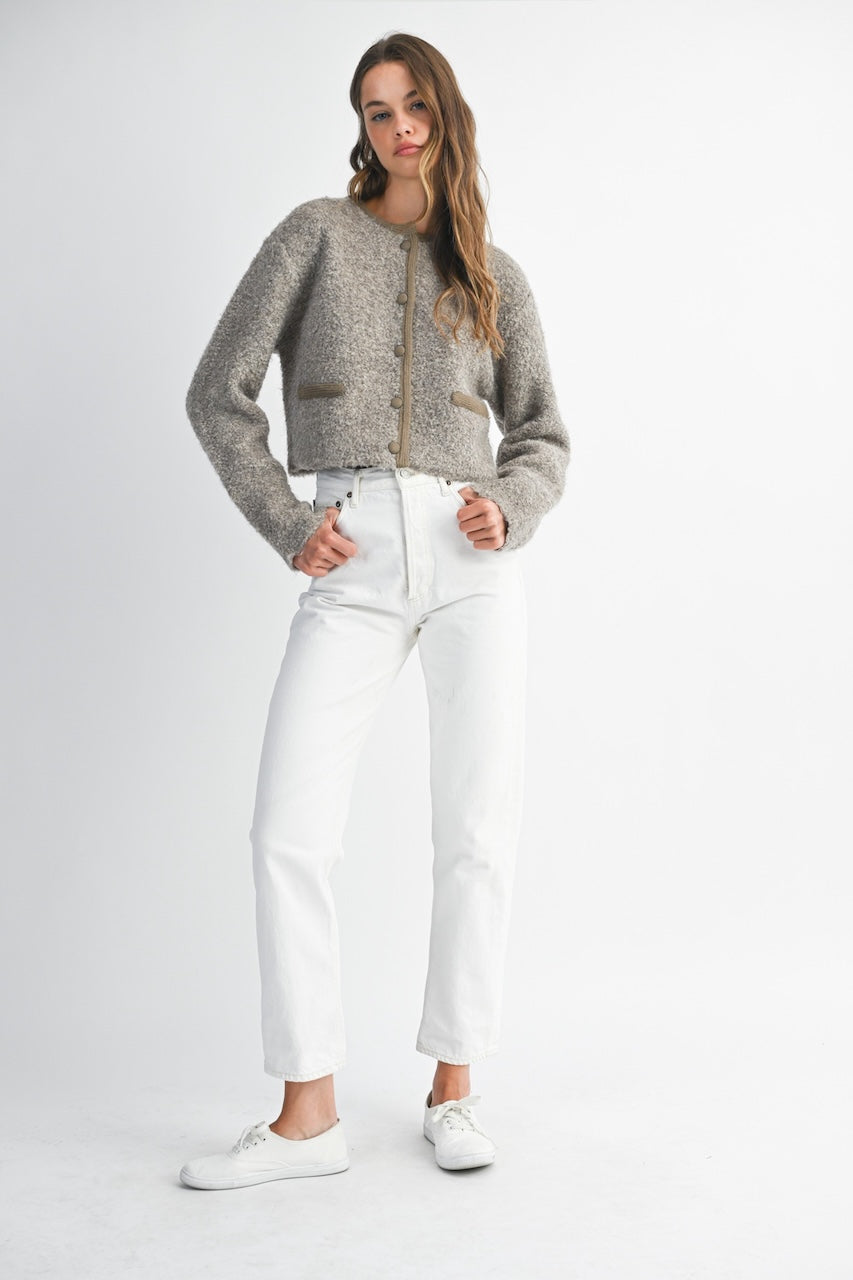Woman wearing a brown knitted texture boucle jacket with brown buttons