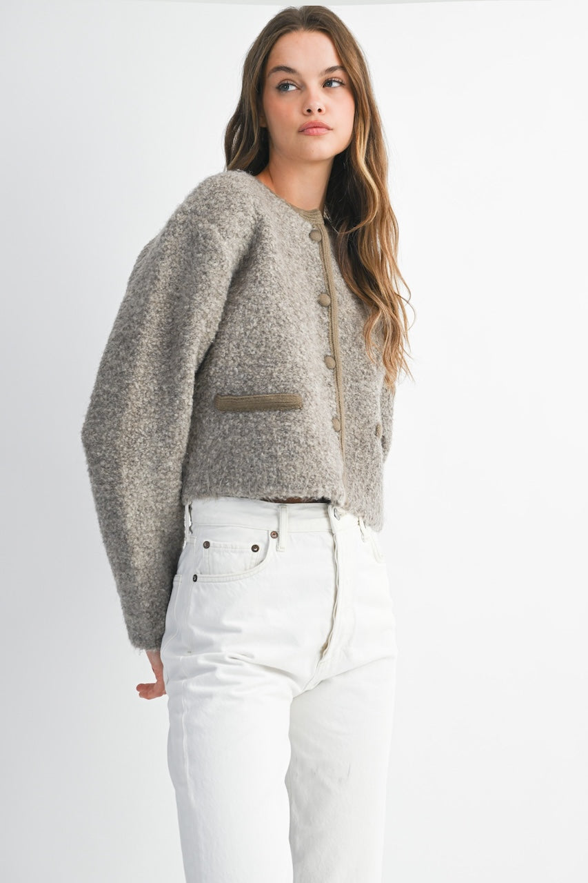 Woman wearing a brown knitted texture boucle jacket with brown buttons