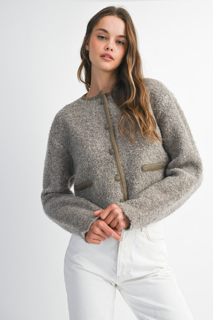 Woman wearing a brown knitted texture boucle jacket with brown buttons