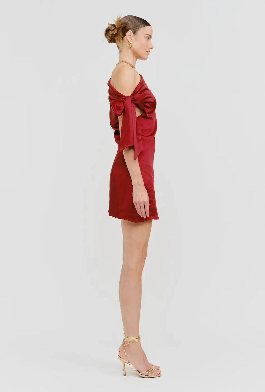 Model wearing red satin one-shoulder mini dress with side bow