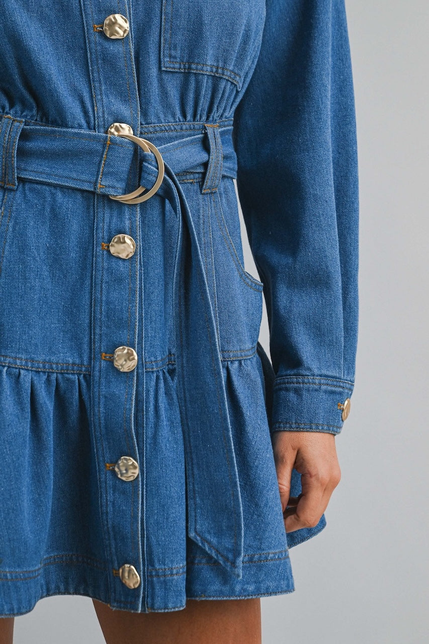 Long sleeve denim mini dress with button down front, collared neckline, D-ring belt, and tiered ruffle hem