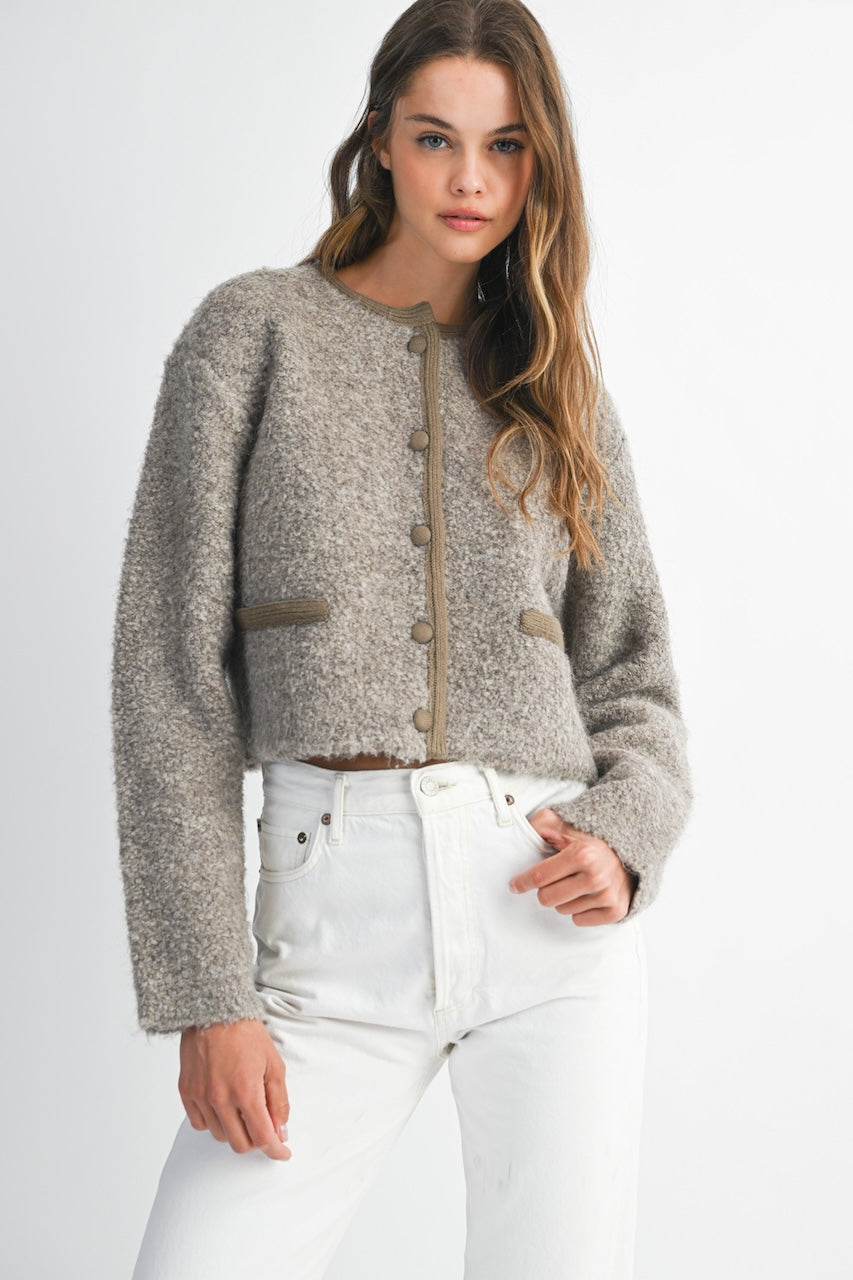 Woman wearing a brown knitted texture boucle jacket with brown buttons