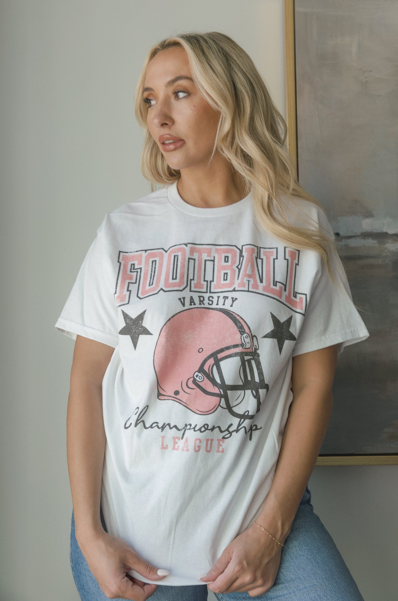 white football graphic tee with a pink football helmet design and football varsity champion league graphic