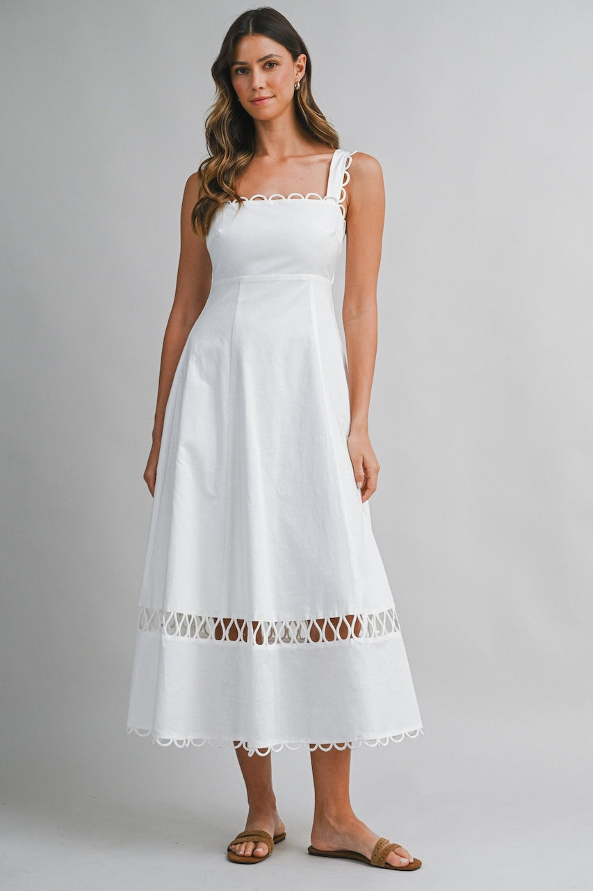 White linen midi dress with square neckline, loop trim straps and scalloped hem on model