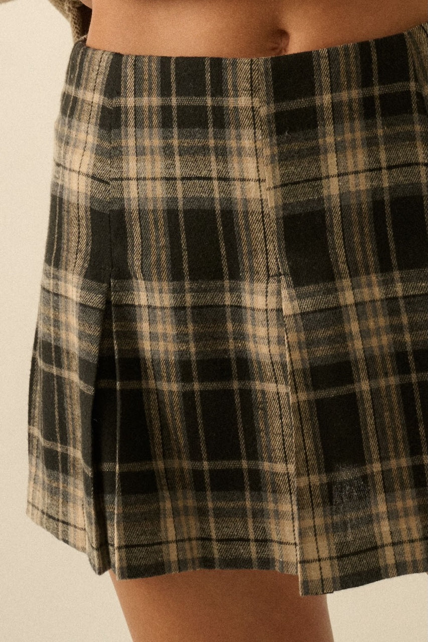 Fall outfit of a woman wearing a plaid mini skirt and beige knee-high boots with a beige oversized sweater