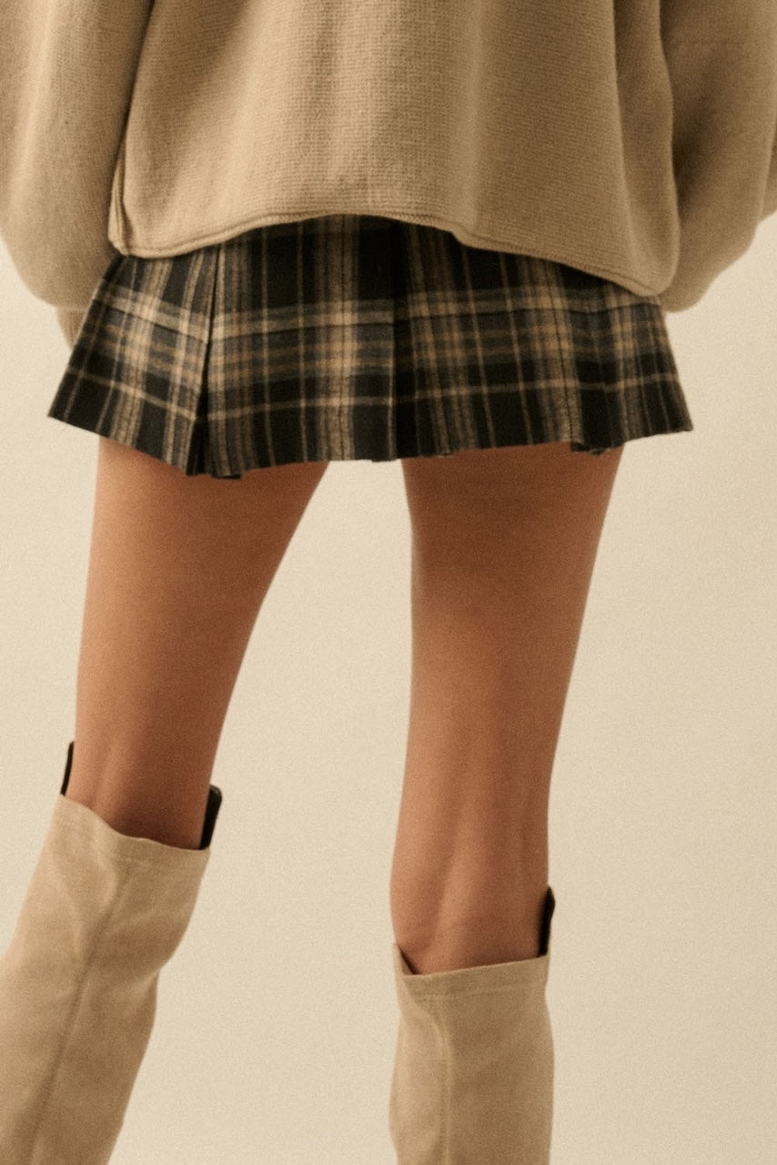 Fall outfit of a woman wearing a plaid mini skirt and beige knee-high boots with a beige oversized sweater