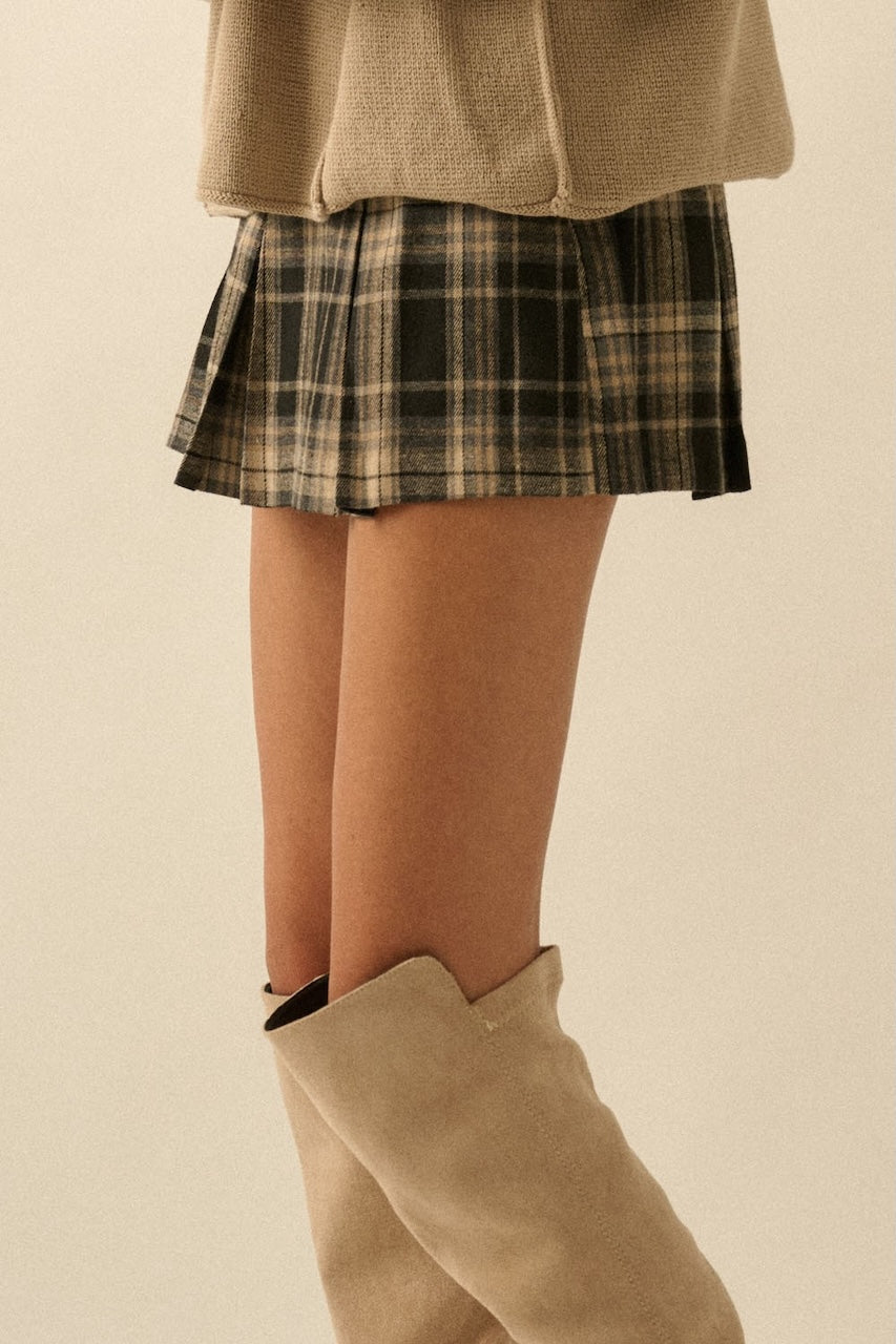Fall outfit of a woman wearing a plaid mini skirt and beige knee-high boots with a beige oversized sweater