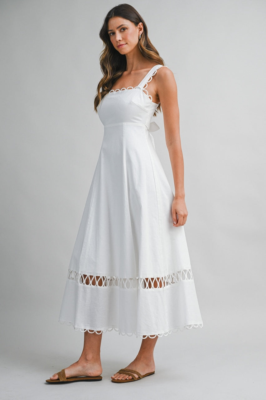 White linen midi dress with square neckline, loop trim straps and scalloped hem on model
