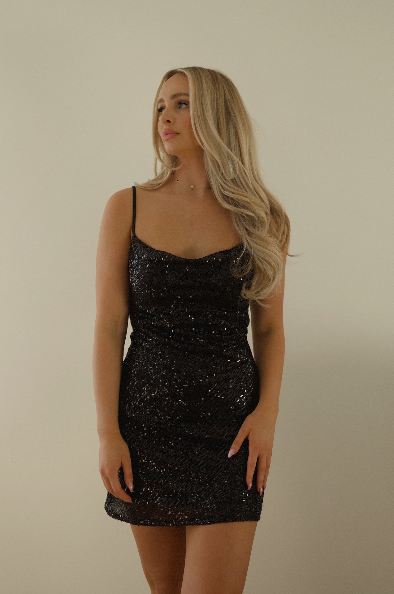 black sequin mini dress with a draped cowl neckline and spaghetti straps