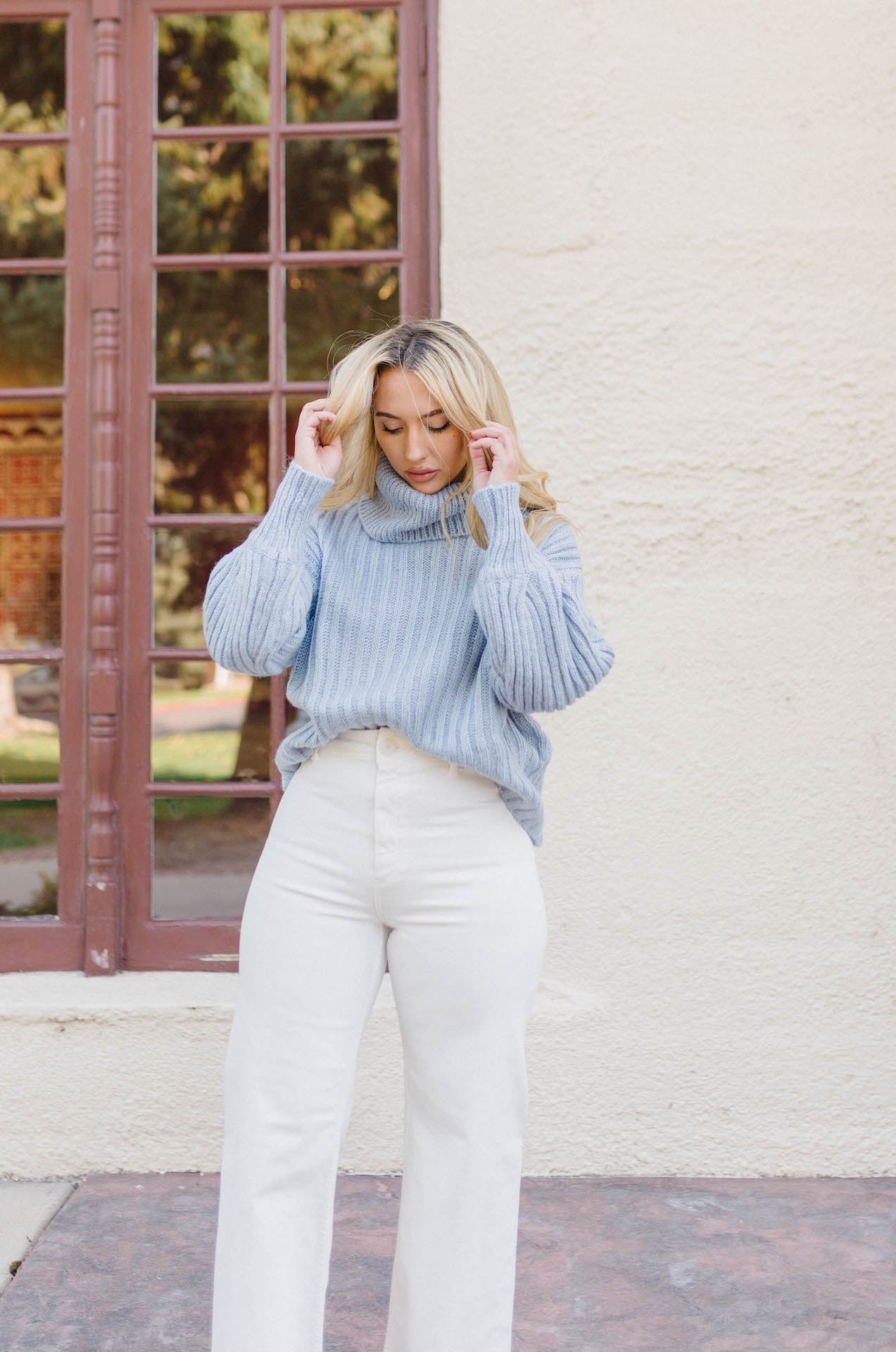 blue ribbed knitted turtleneck sweater with long sleeves paired with white high waisted wide leg jeans