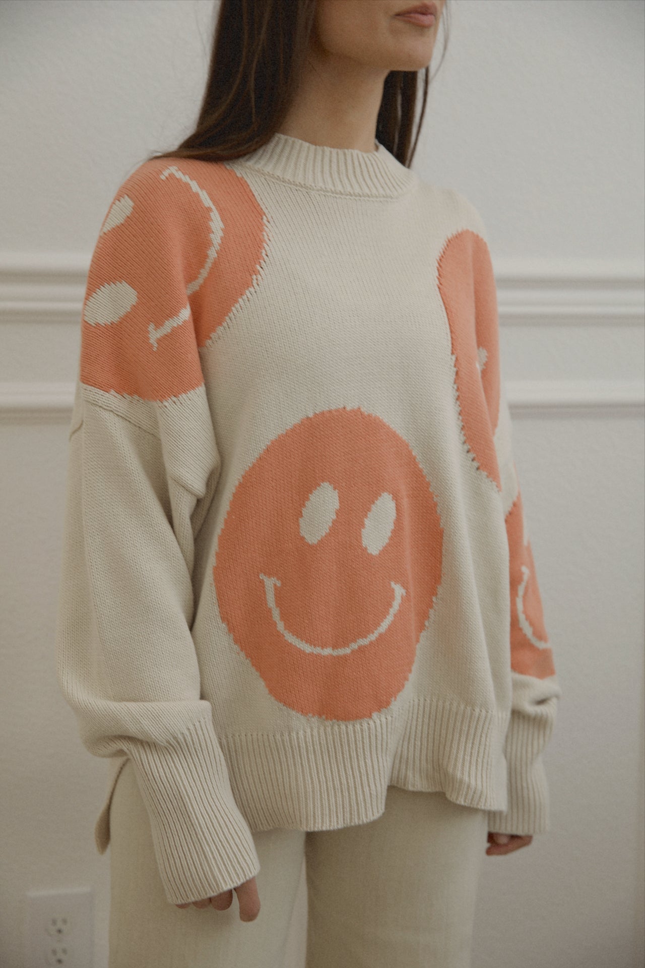 orange smiley face sweater with a mock neckline and an oversized fit