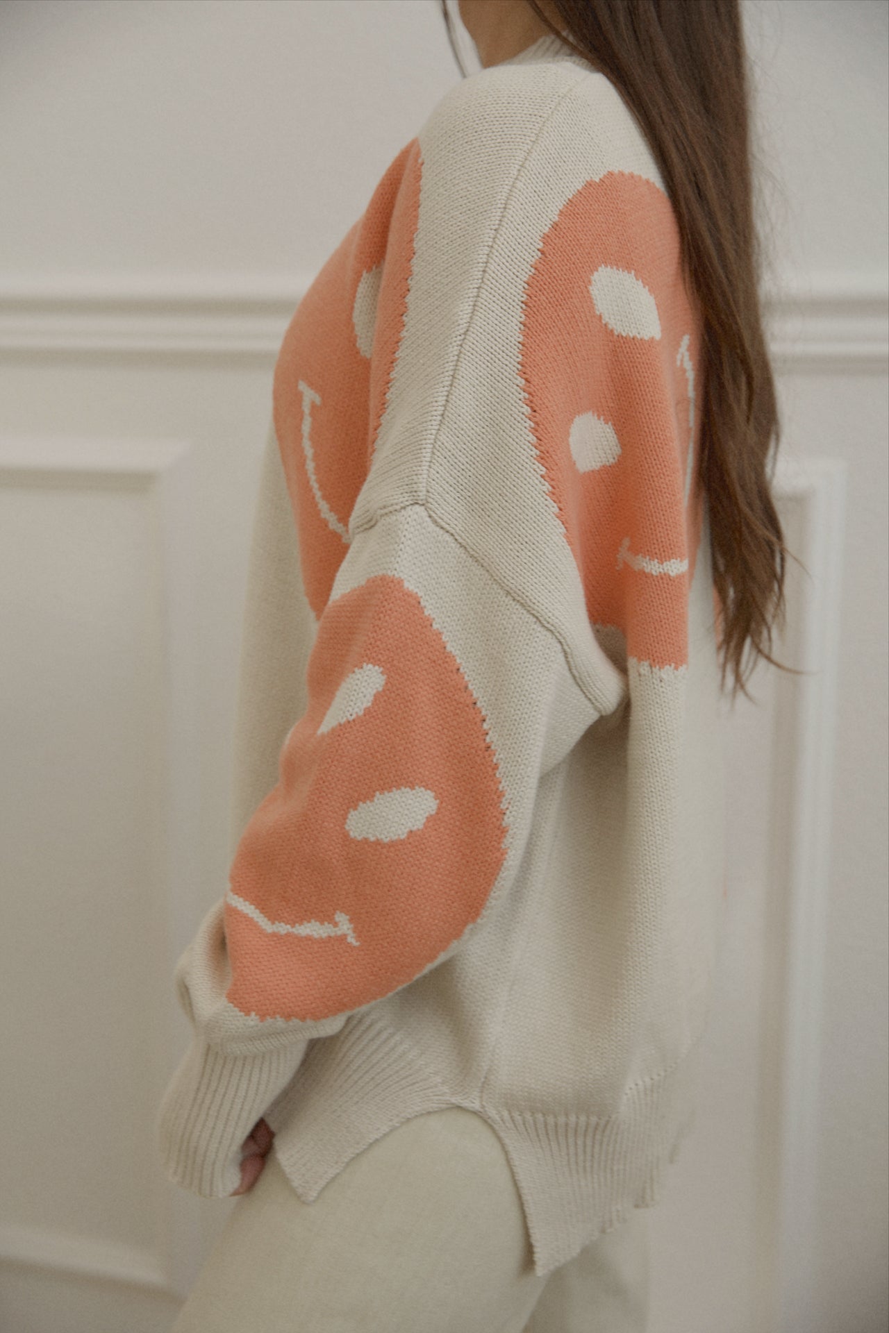 orange smiley face sweater with a mock neckline and an oversized fit