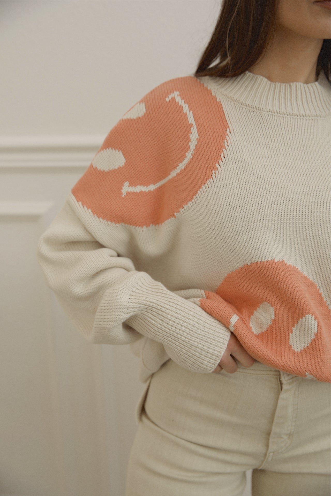 orange smiley face sweater with a mock neckline and an oversized fit