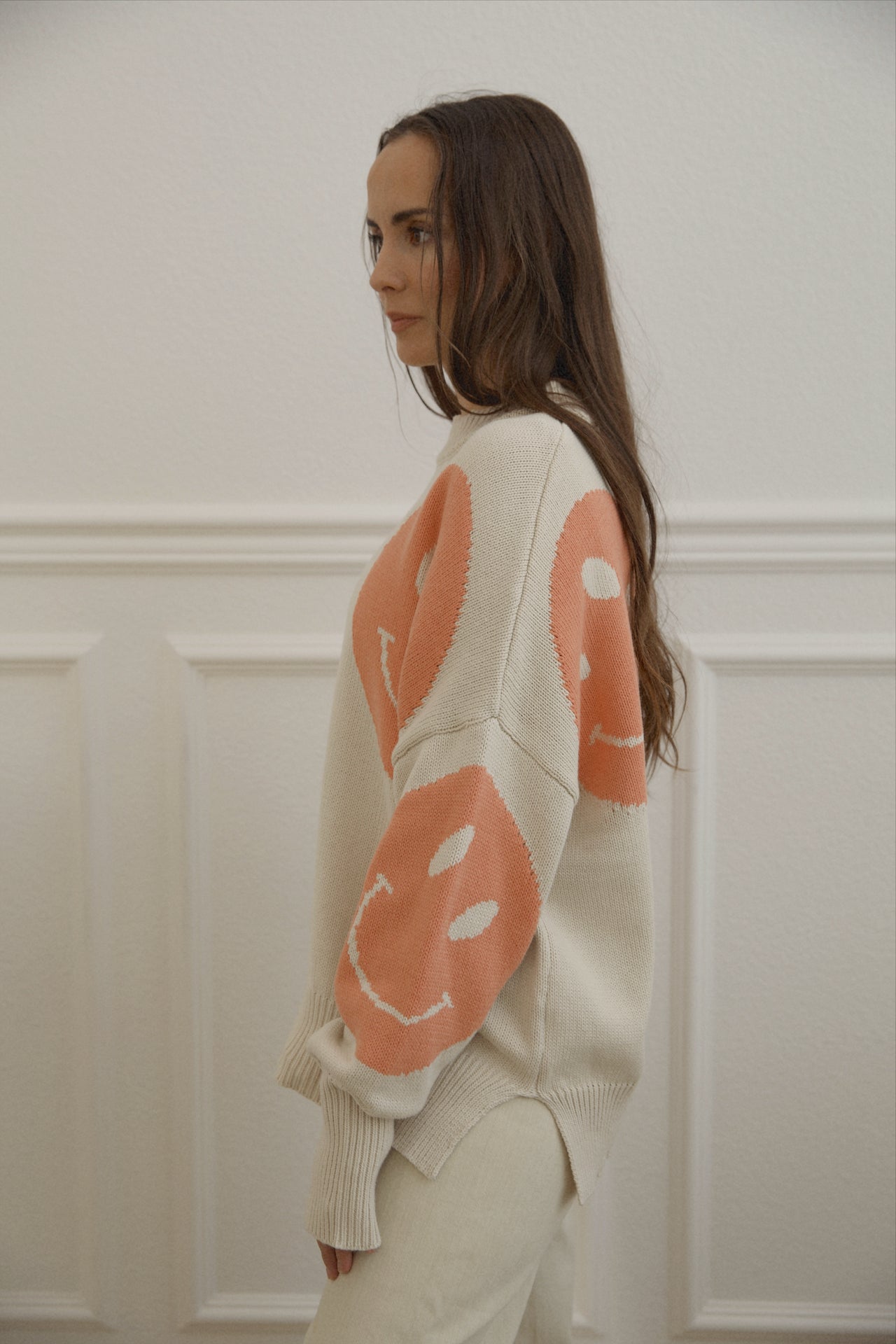 orange smiley face sweater with a mock neckline and an oversized fit