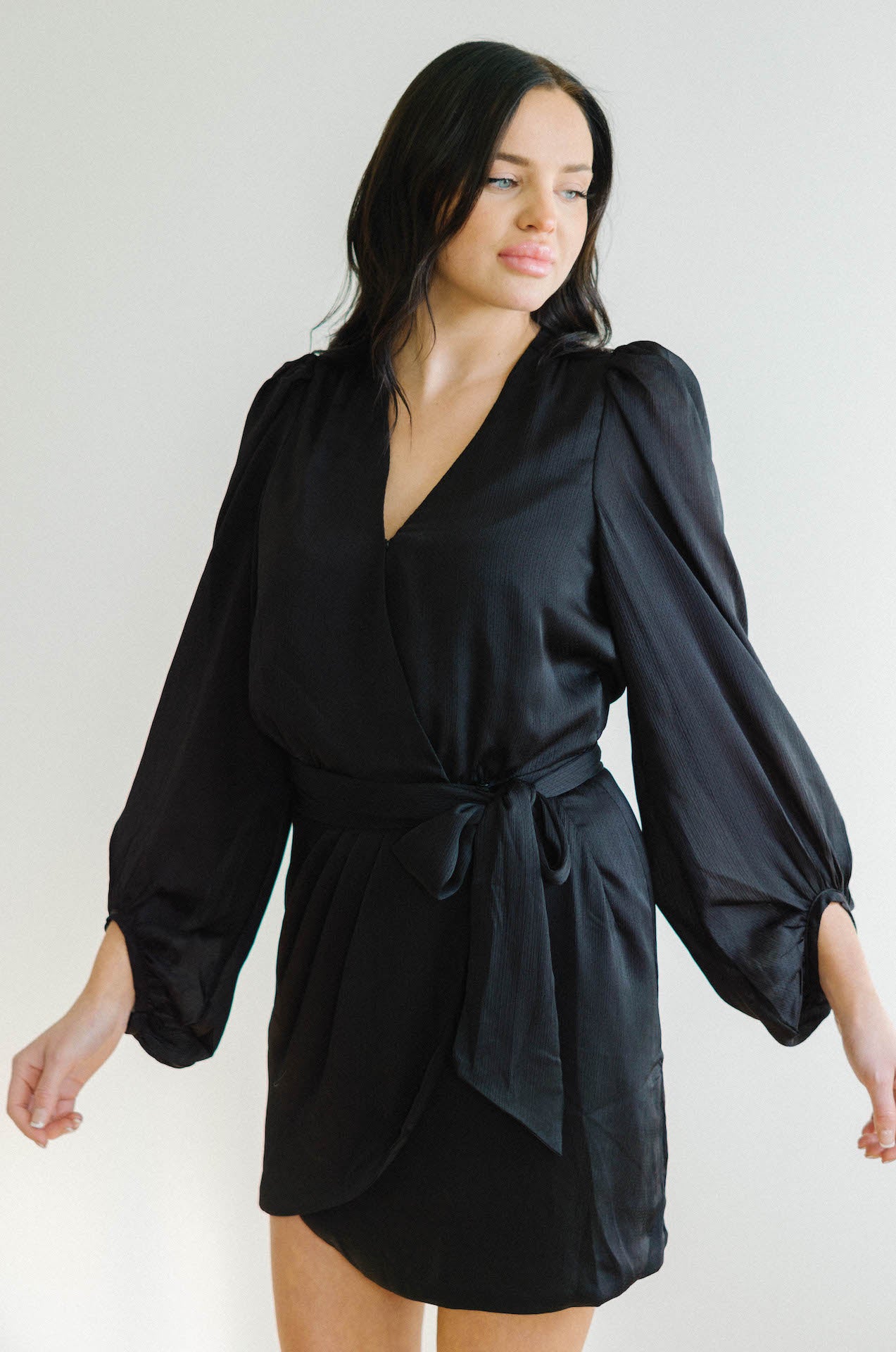 black wrap mini dress with long sleeves and a pin dot design throughout