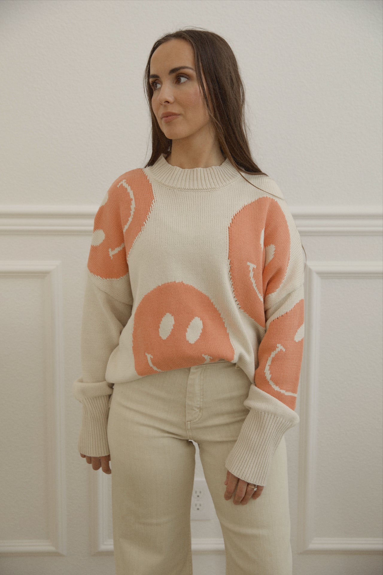 orange smiley face sweater with a mock neckline and an oversized fit