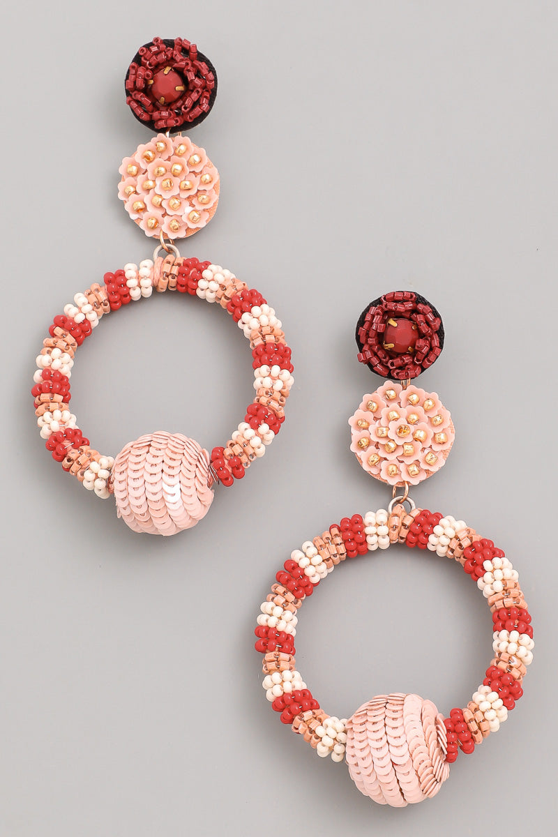 A pair of beaded dangle earrings with a floral design, featuring red, blush, and white beads.