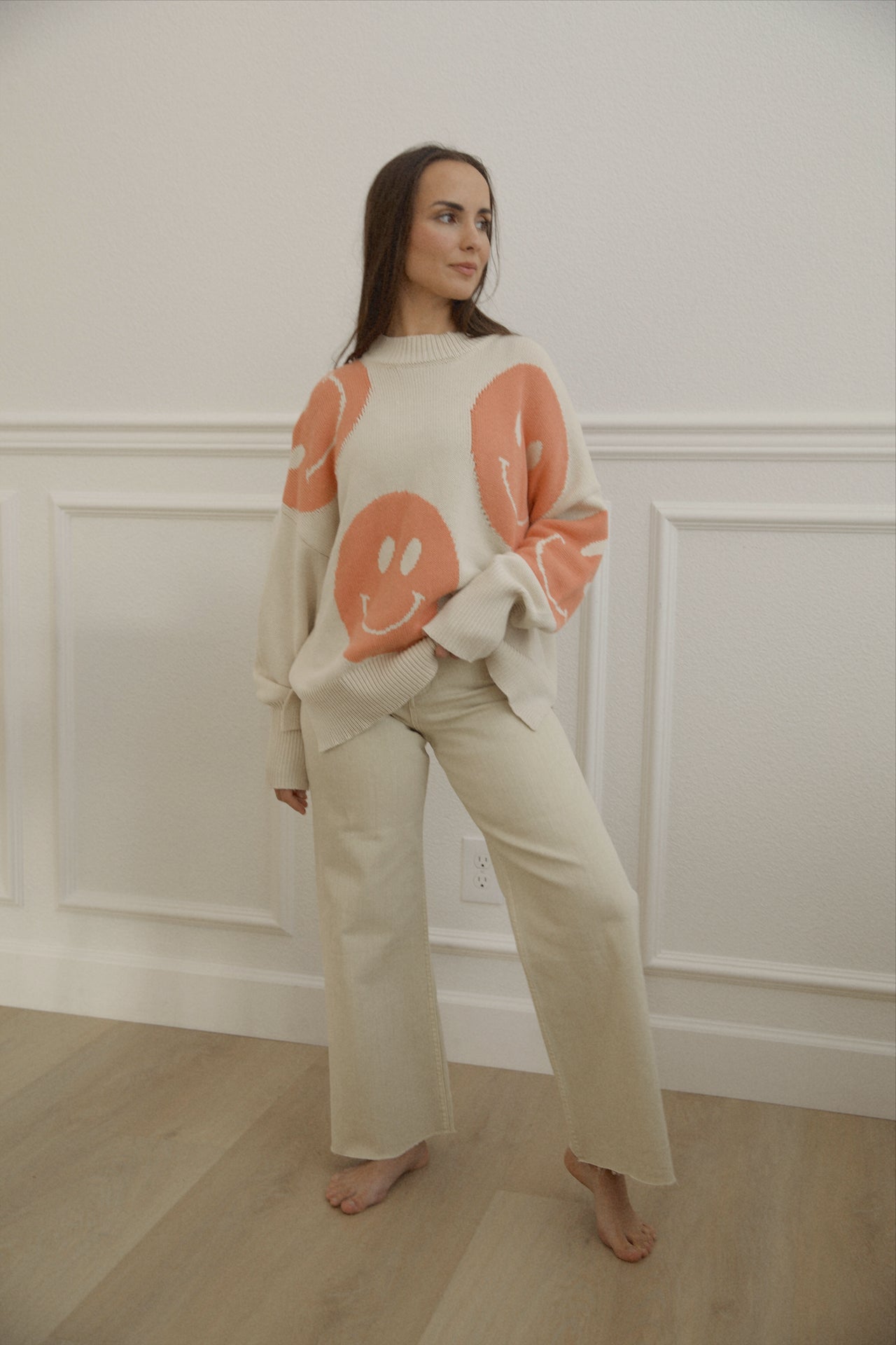 orange smiley face sweater with a mock neckline and an oversized fit