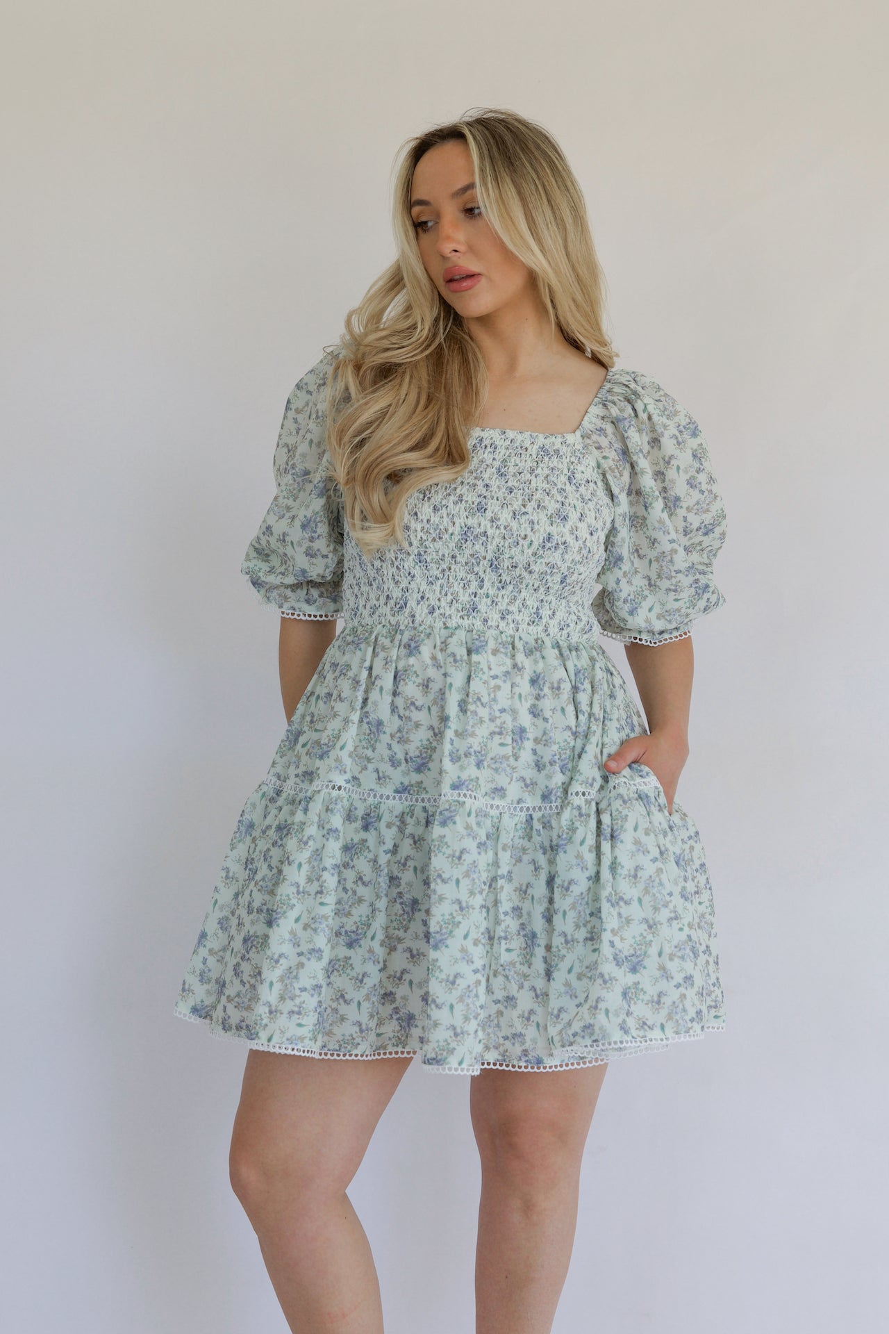blue floral mini dress with puff sleeves, smocked bodice, tiered, and crochet lace trim