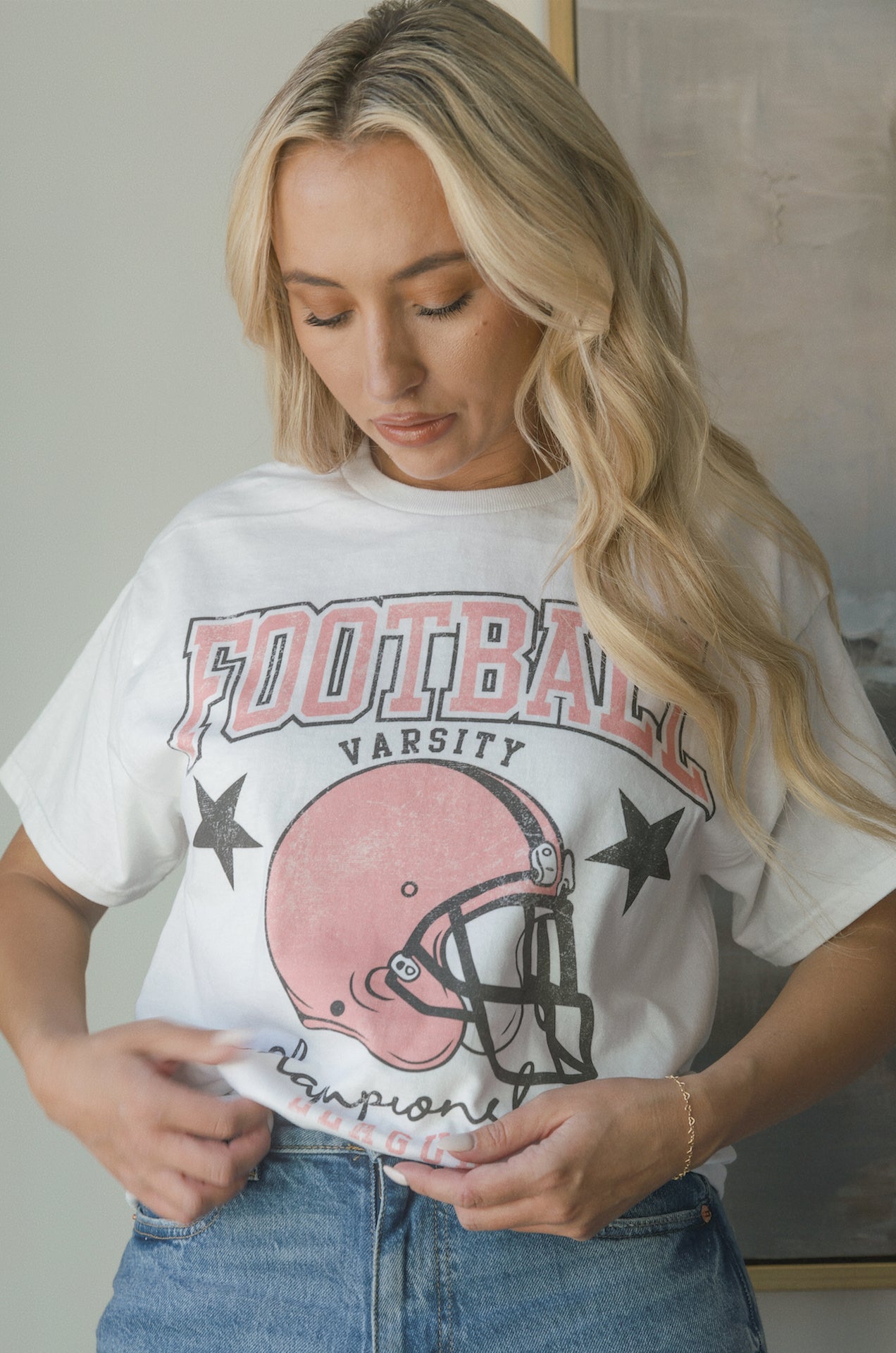 white football graphic tee with a pink football helmet design and football varsity champion league graphic