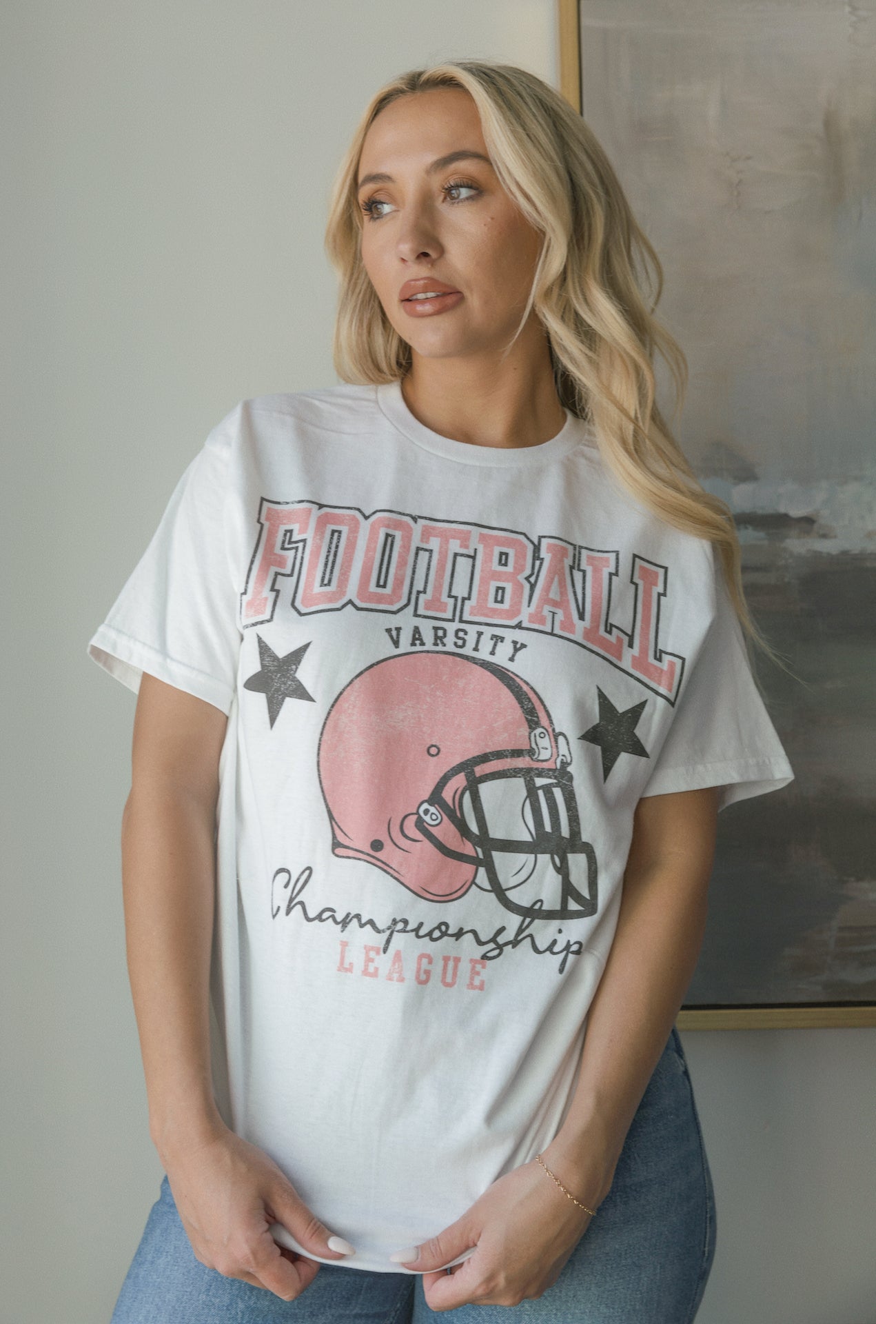 white football graphic tee with a pink football helmet design and football varsity champion league graphic