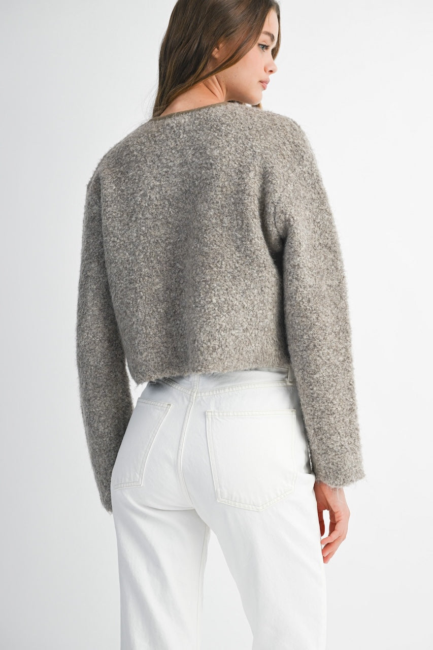 Woman wearing a brown knitted texture boucle jacket with brown buttons