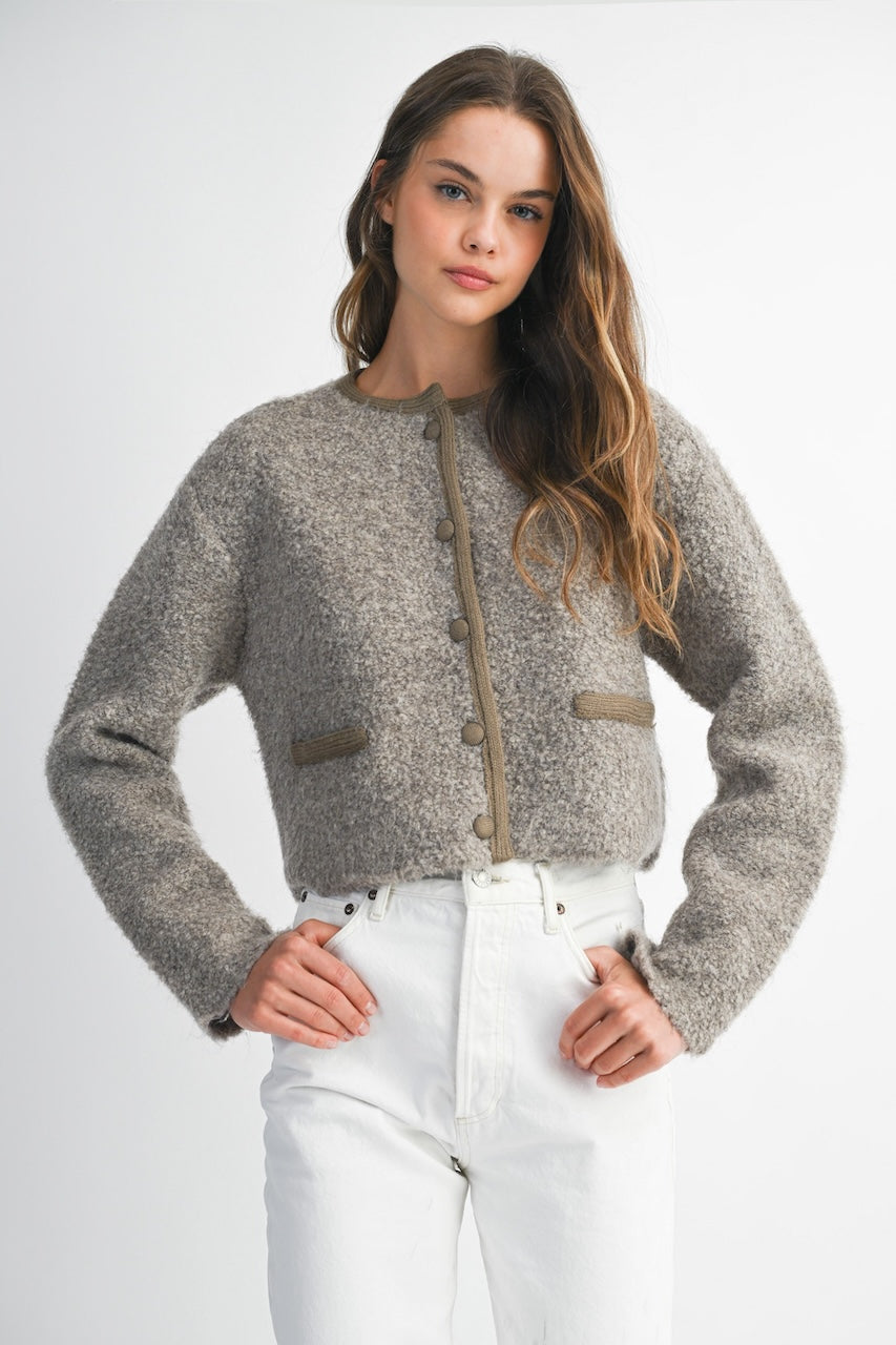 Woman wearing a brown knitted texture boucle jacket with brown buttons