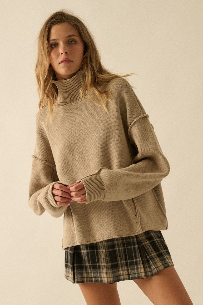 Fall outfit of a woman wearing a plaid mini skirt and beige knee-high boots with a beige oversized sweater