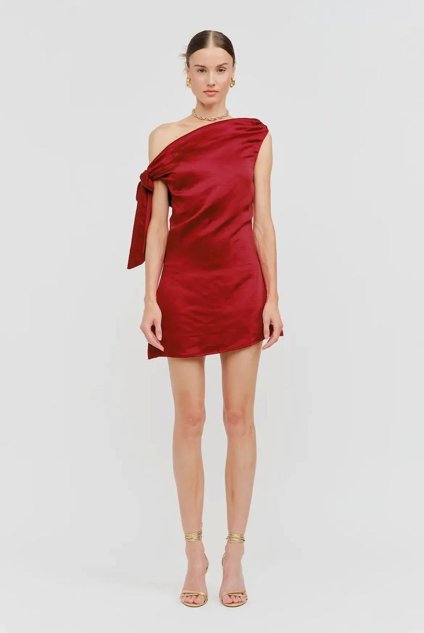 Model wearing red satin one-shoulder mini dress with side bow