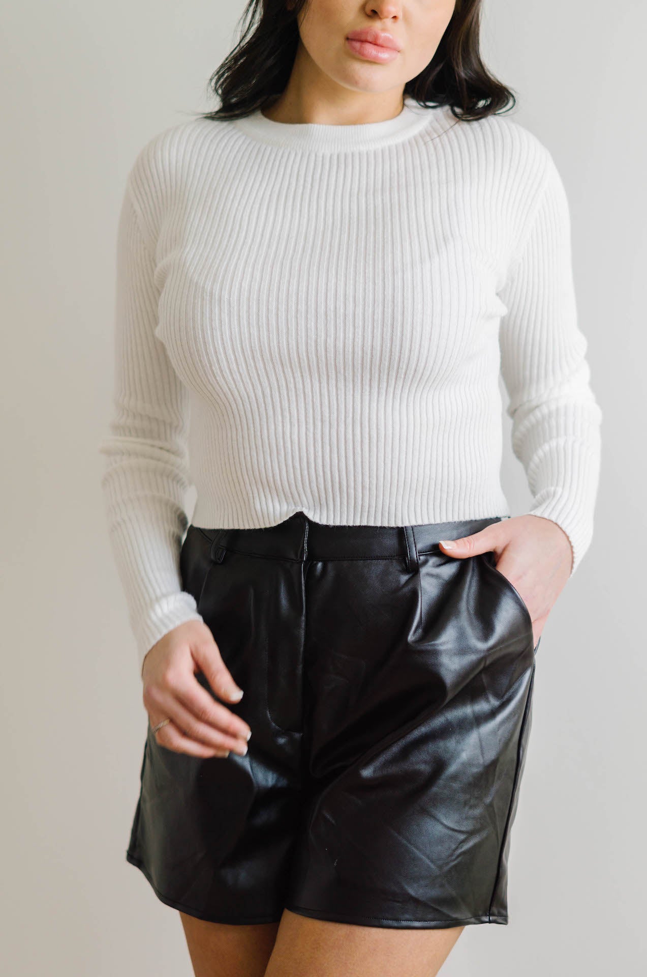 white long sleeve ribbed sweater top paired with vegan black leather shorts