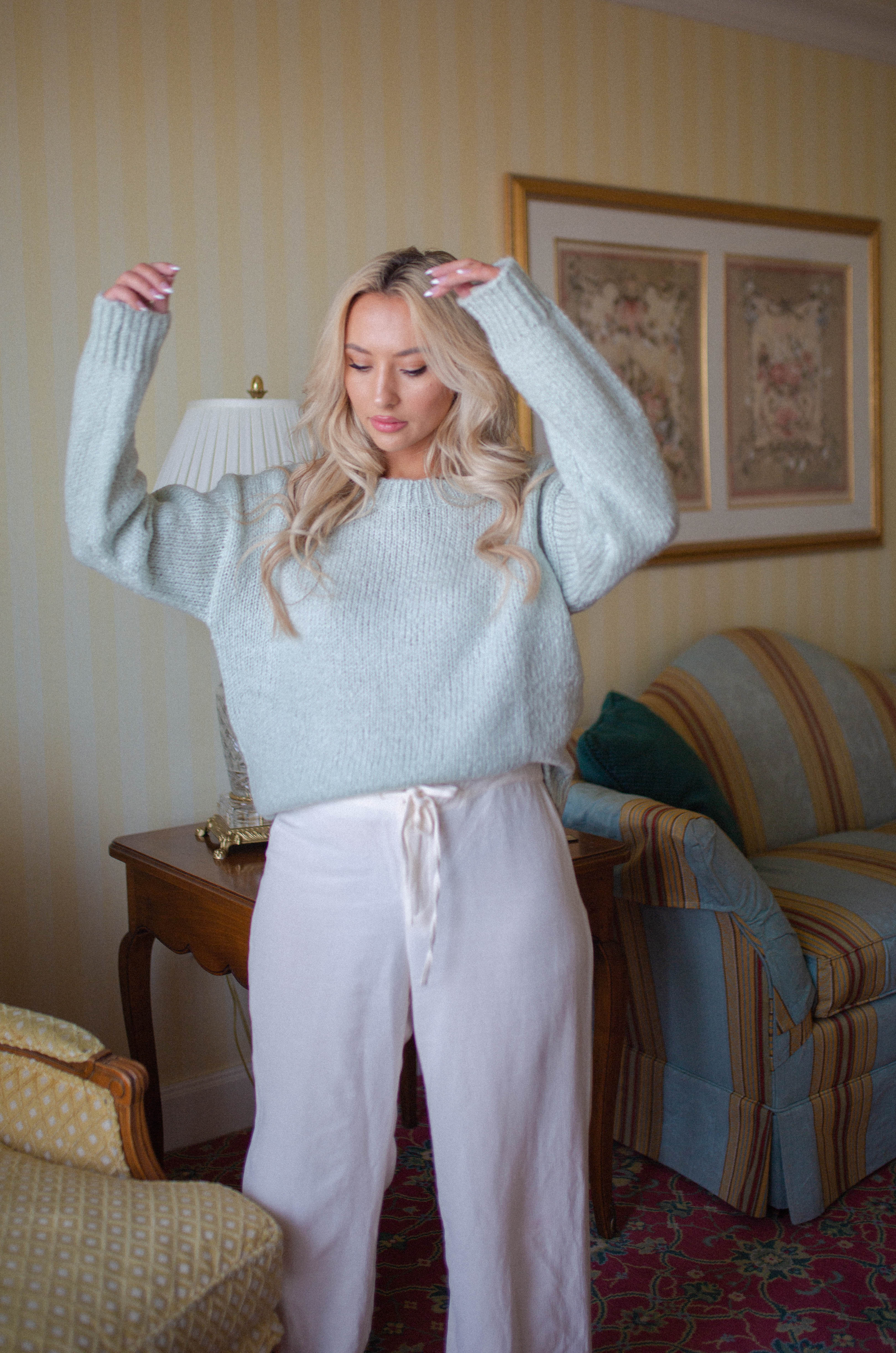 comfy and cozy stylish outfit featuring white silk pants and a mint sage knit crew neckline sweater