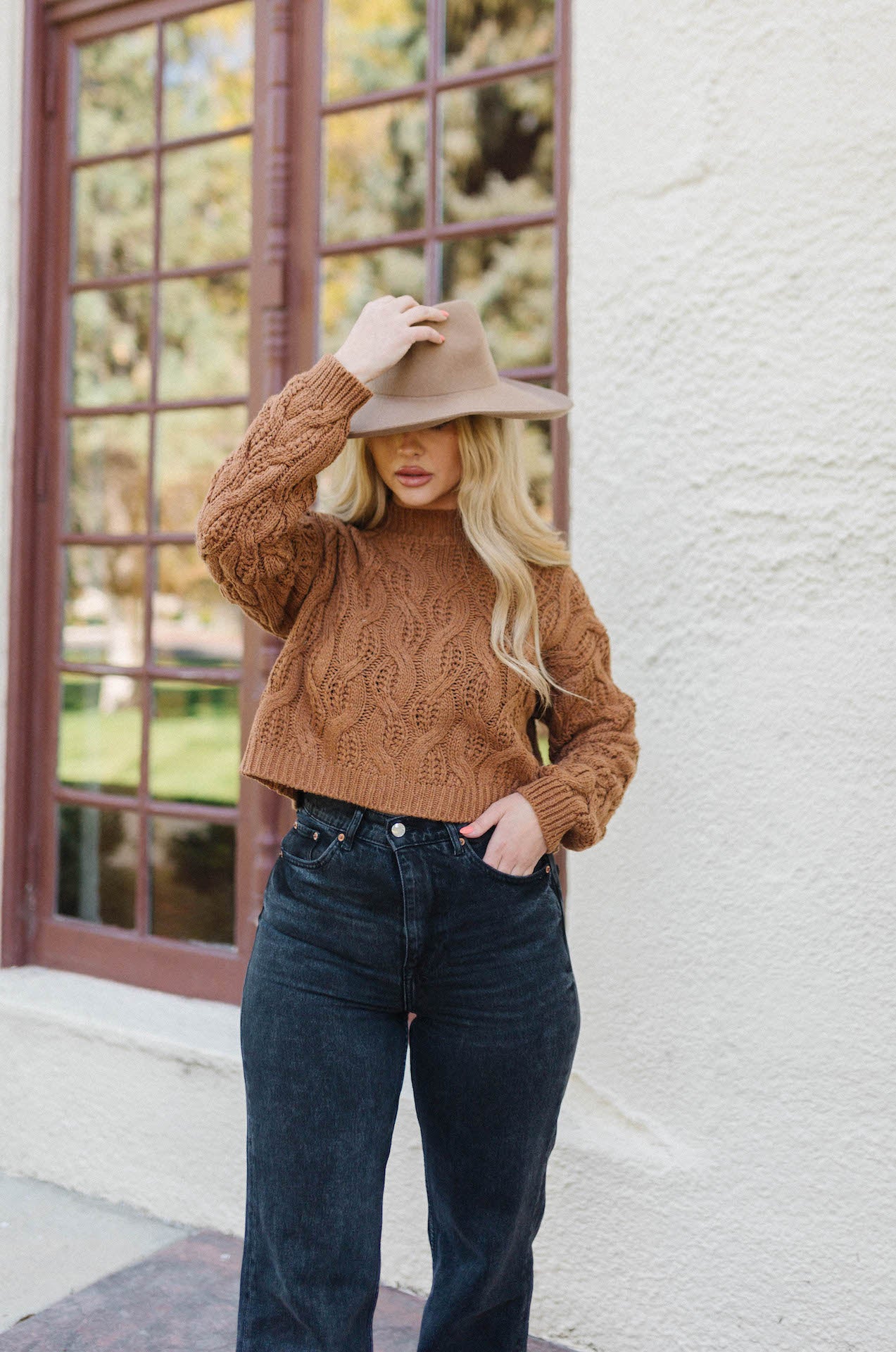 brown cable knit sweater paired with high waisted straight leg jeans and a brown wool hat