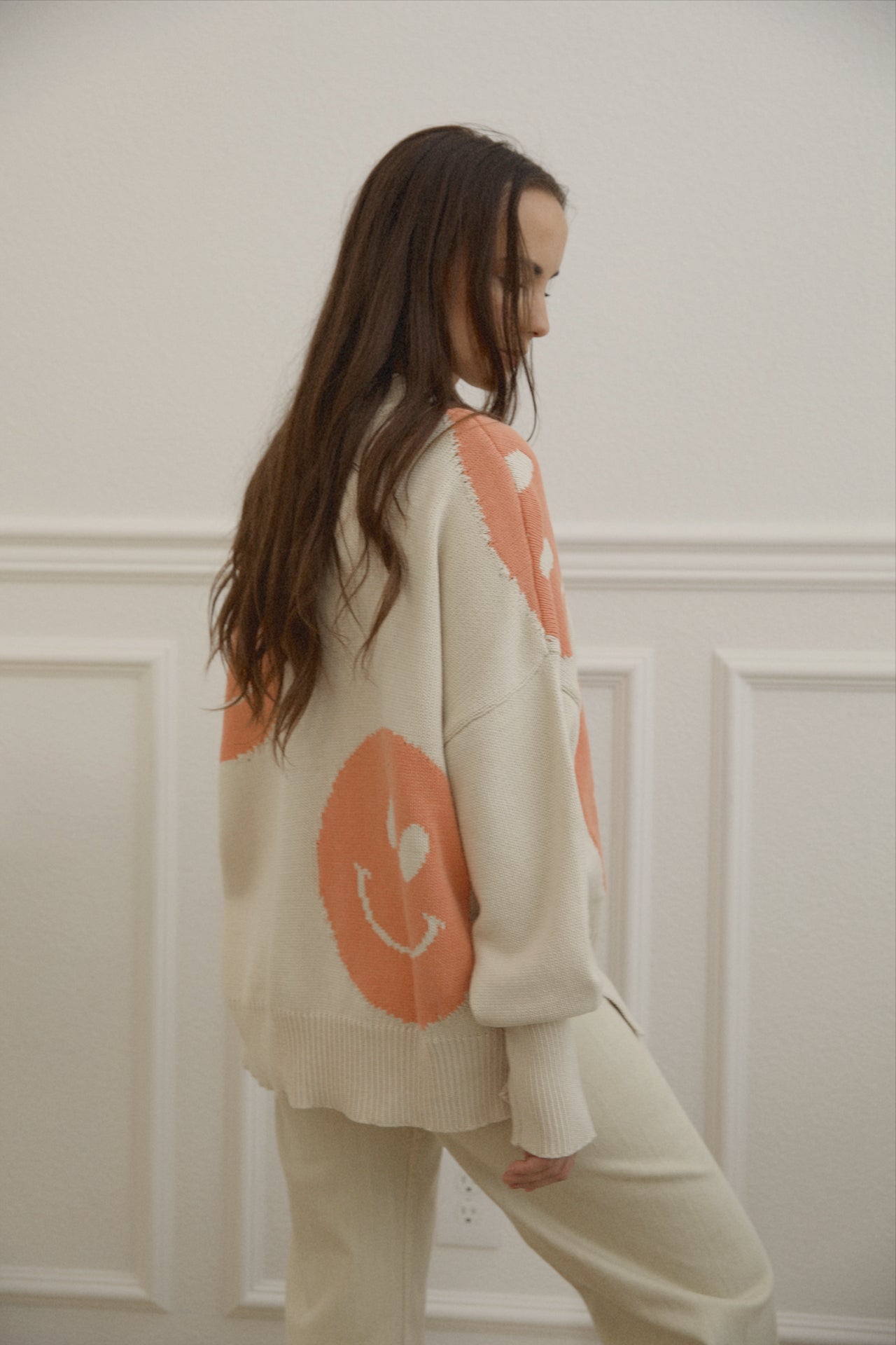 orange smiley face sweater with a mock neckline and an oversized fit