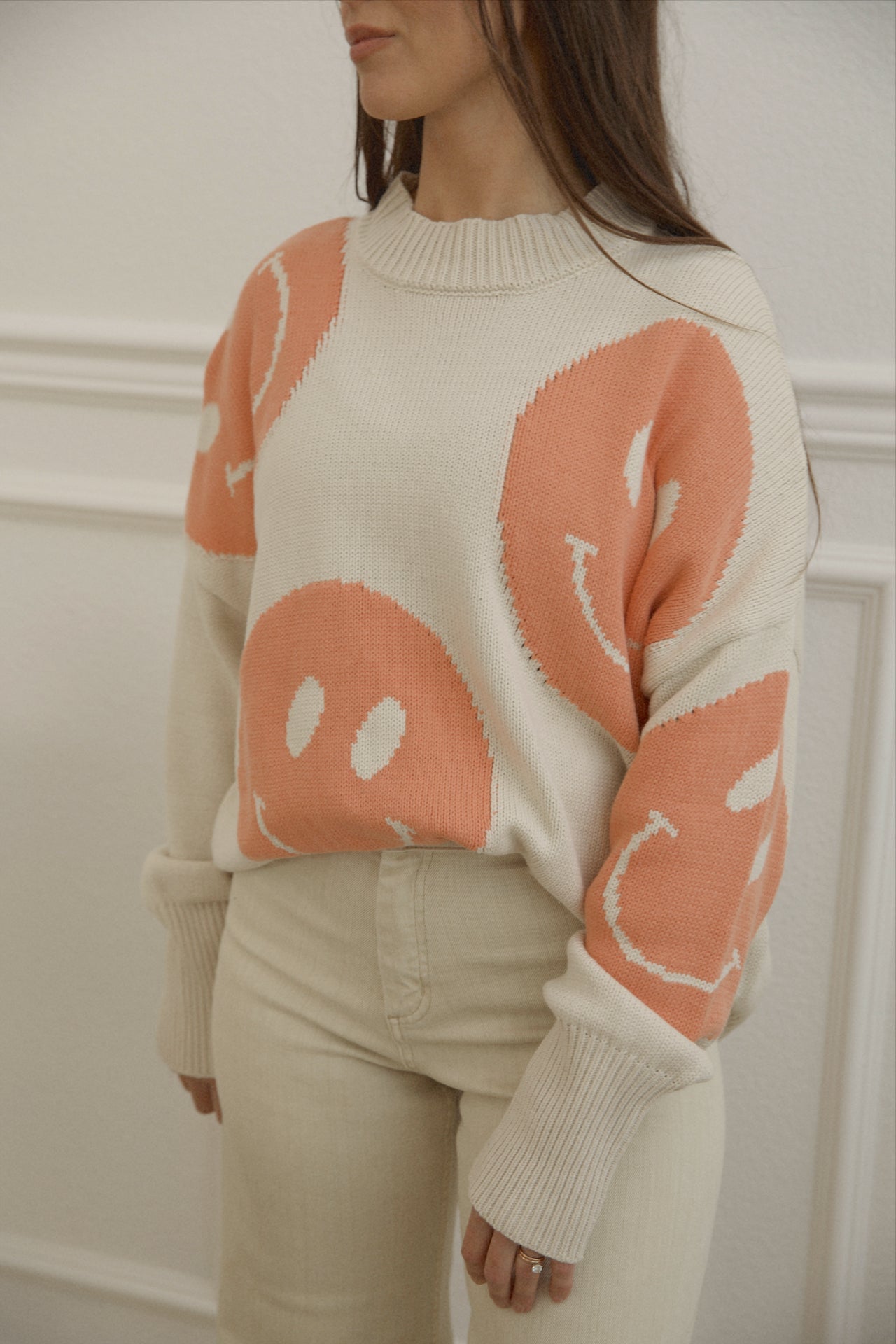 orange smiley face sweater with a mock neckline and an oversized fit