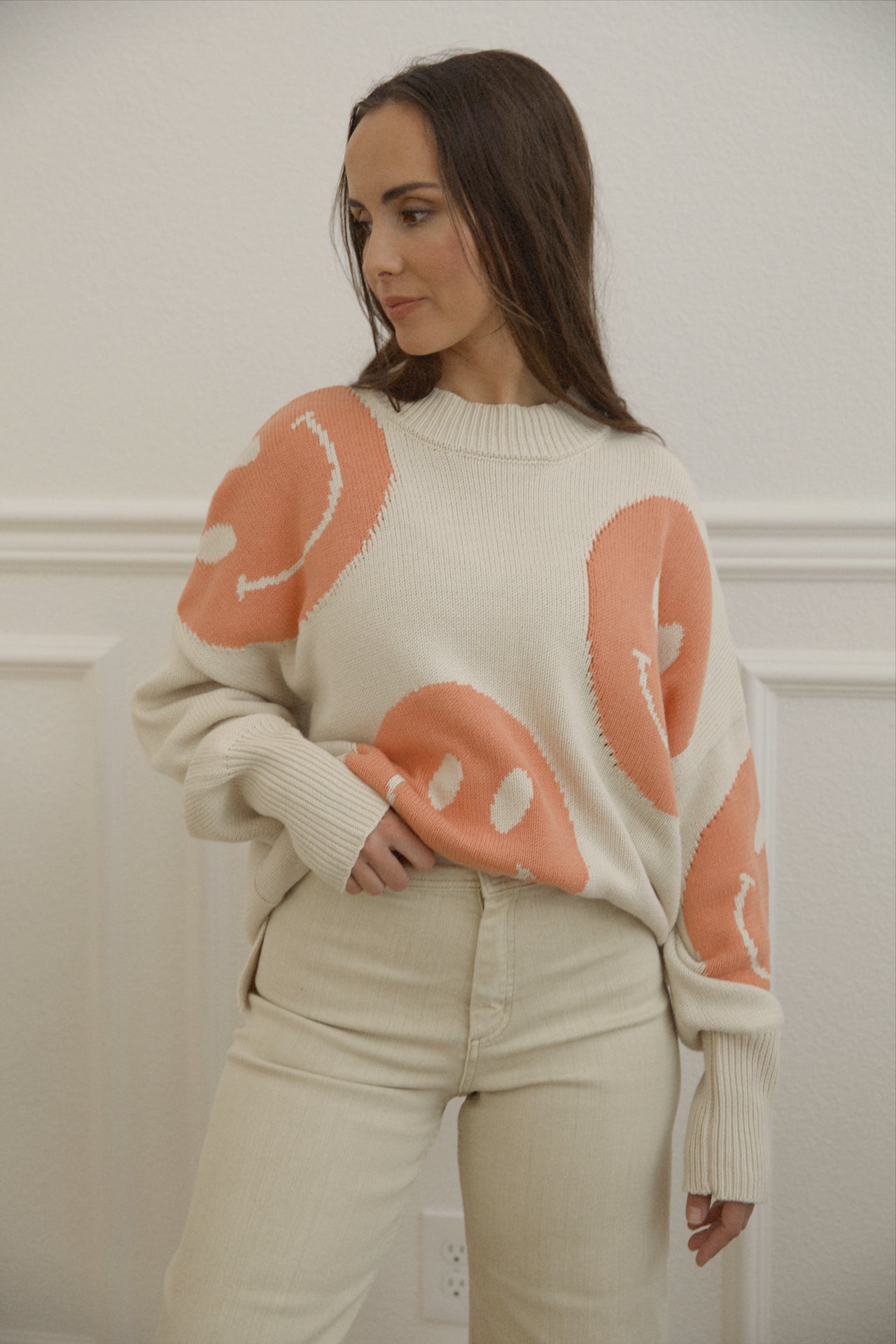 orange smiley face sweater with a mock neckline and an oversized fit