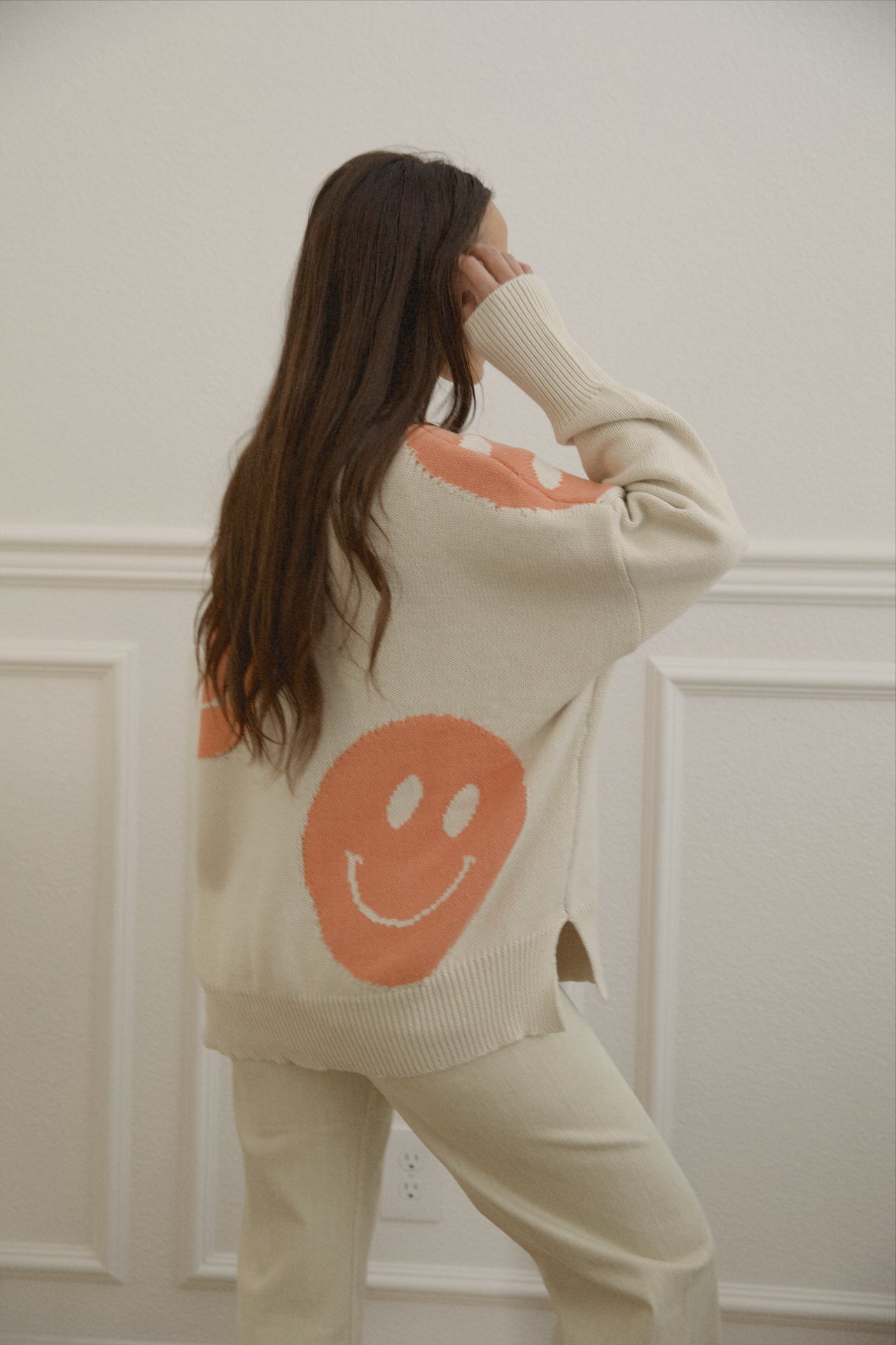 orange smiley face sweater with a mock neckline and an oversized fit