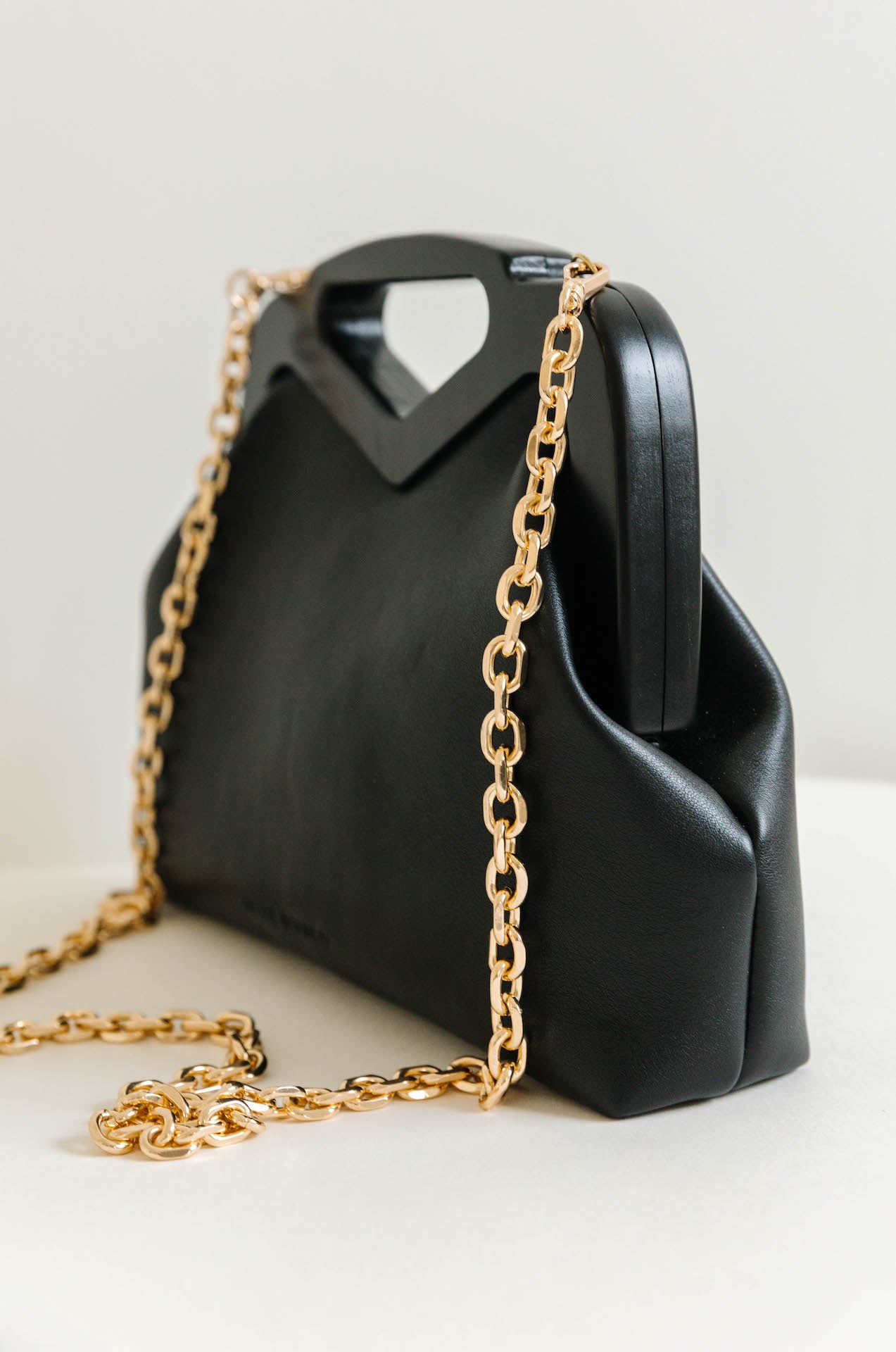 black vegan leather triangle top handle bag with gold chain